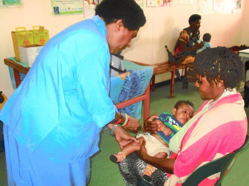 A mother comforts her child as she is being immunised against measles by Community Health Worker, Yari Kila at the Mt Hagen Urban Clinic.