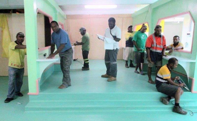Employees of Kameka Builders putting on the finishing touches to the A&E Unit while WHPHA’s Project Management Unit team leader, Kenneth Nabuga (standing centre looking at building plan) checks to ensure all jobs have been completed according to plan.
