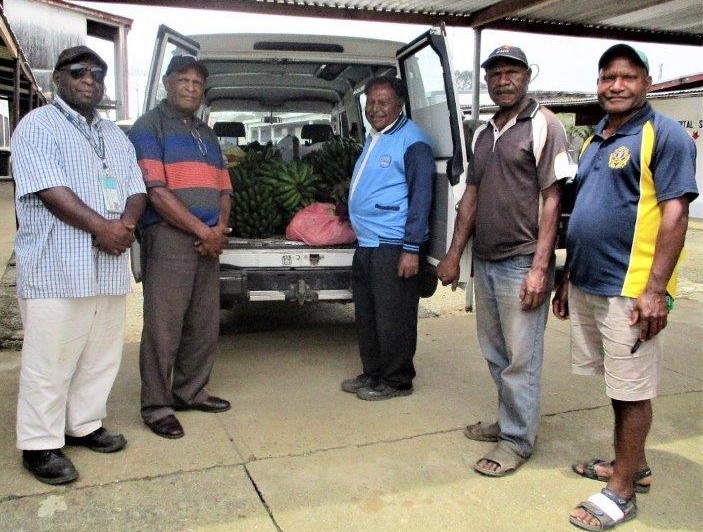 Dei District Health Officer, Smee Rank (left) accepting the food from the Assistant District Administrator for Dei, Raphael Koldop (standing next to him) watched by other senior public servants of Dei District.
