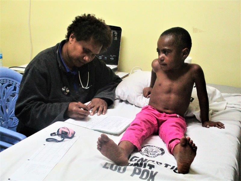 The child sits up as Dr Kilalang notes her findings in his clinical book.
