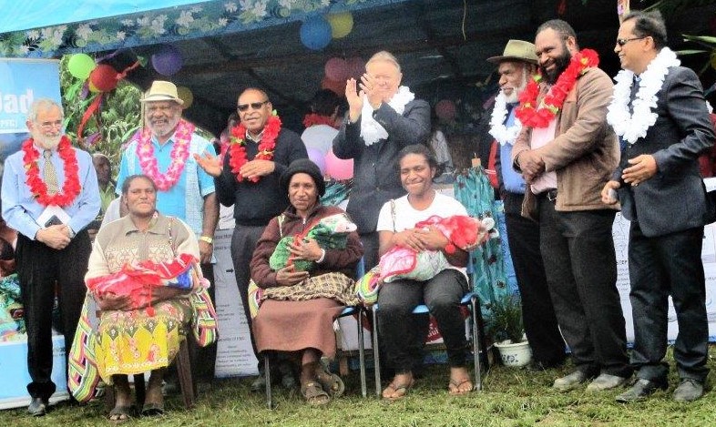 Three mothers trying out the Bebi Kol Kilok on their babies, watched by officials.