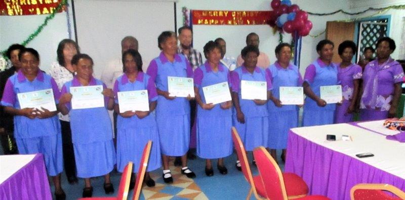 The eight graduates proudly displaying their certificates with Professor Glen Mola standing in the back centre.