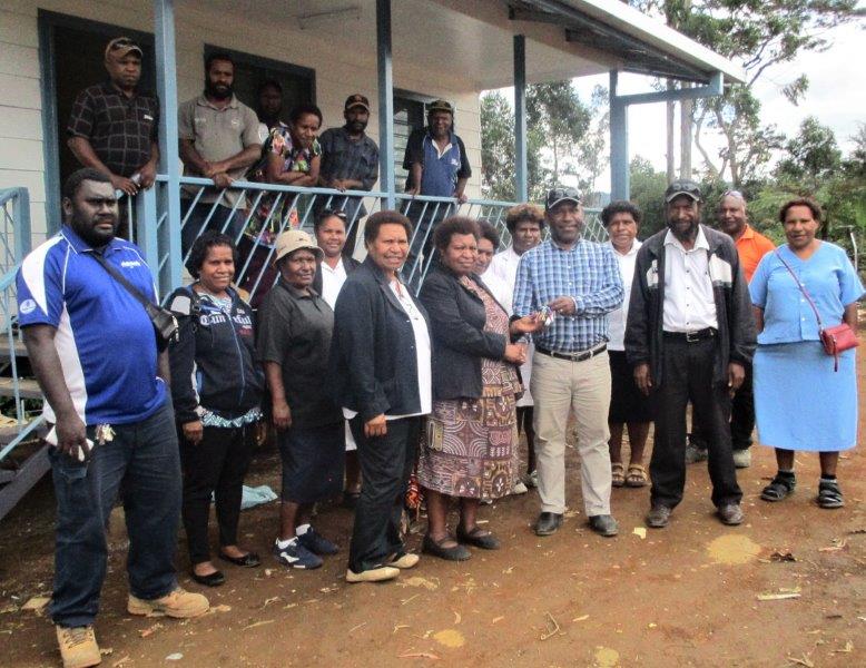 Acting director of nursing with WHPHA, Sr. Janet Yamu receiving the keys to the new house from Stewart Construction owner, Paul Berry, witnessed by other nurses and support staff.