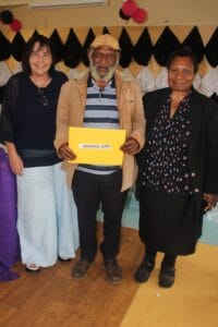 Retiree (Michael Atep) standing between WHPHA’s acting CEO Jane Holden (left) and Director of Nursing Services Sr. Janet Yamu