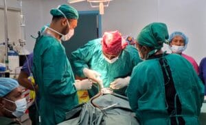 Visiting surgeon Dr. Jackson Nuli (middle) performs surgery on a patient while Dr Johns and Sr Raim assist