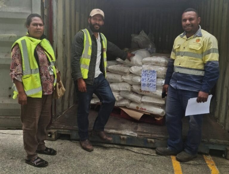 R-L Health Inspectors (Melissa and Joe) with Mr Kalip at the Trukai Depot in Mt Hagen, standing beside spoiled rice products