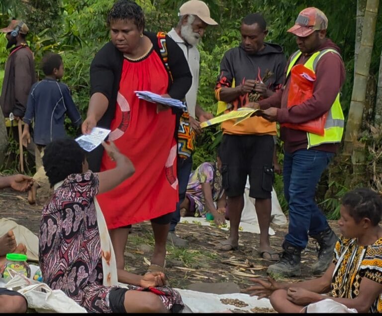 Ms Josephine Gabuzzi disseminating brochures and information papers on cervical cancer to members of the Nengil community in Baiyer during Cervical Cancer Awareness Month